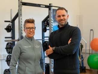 Presenter Manuel Rothmund stands in a fitness room together with physiotherapist Lea Nadig
