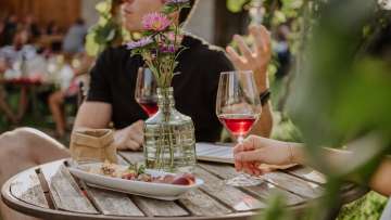 Couple sitting at a wooden table with summer decorations, snacks and a glass of wine