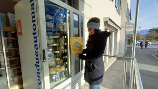 Woman standing in front of the fondue machine in Bad Ragaz. She is holding a packet containing a fondue mixture