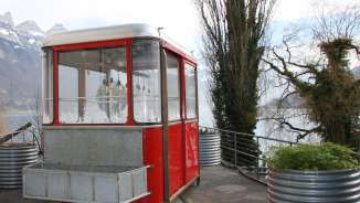 A red gondola that has been converted into a fondue restaurant stands on the shore of Lake Walen