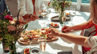 A sumptuous aperitif platter is served on the Walensee boat. Several people sit at the table, which is decorated with flowers and wine glasses.