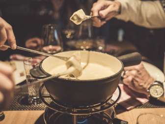 Several people enjoy a cheese fondue