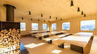 Lounge of a group accommodation with large tables and fireplace