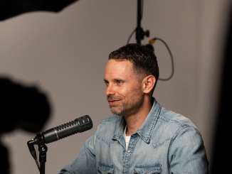 Presenter Manuel Rothmund sits in front of the podcast microphone in the podcast studio