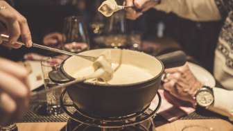 Several people enjoy a cheese fondue