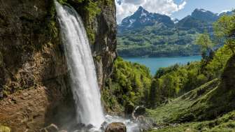 The thundering waterfall of the Rhinquelle with a view of Lake Walen and the striking Mürtschenstock