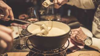 Several people enjoy a cheese fondue